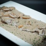 A dish with mushrooms and gravy on a white plate.