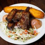 A plate with ribs and coleslaw on it.