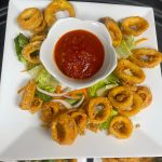 A plate of fried octopus rings with dipping sauce.