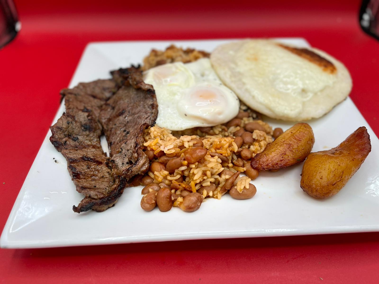 A plate with steak, beans and eggs on it.