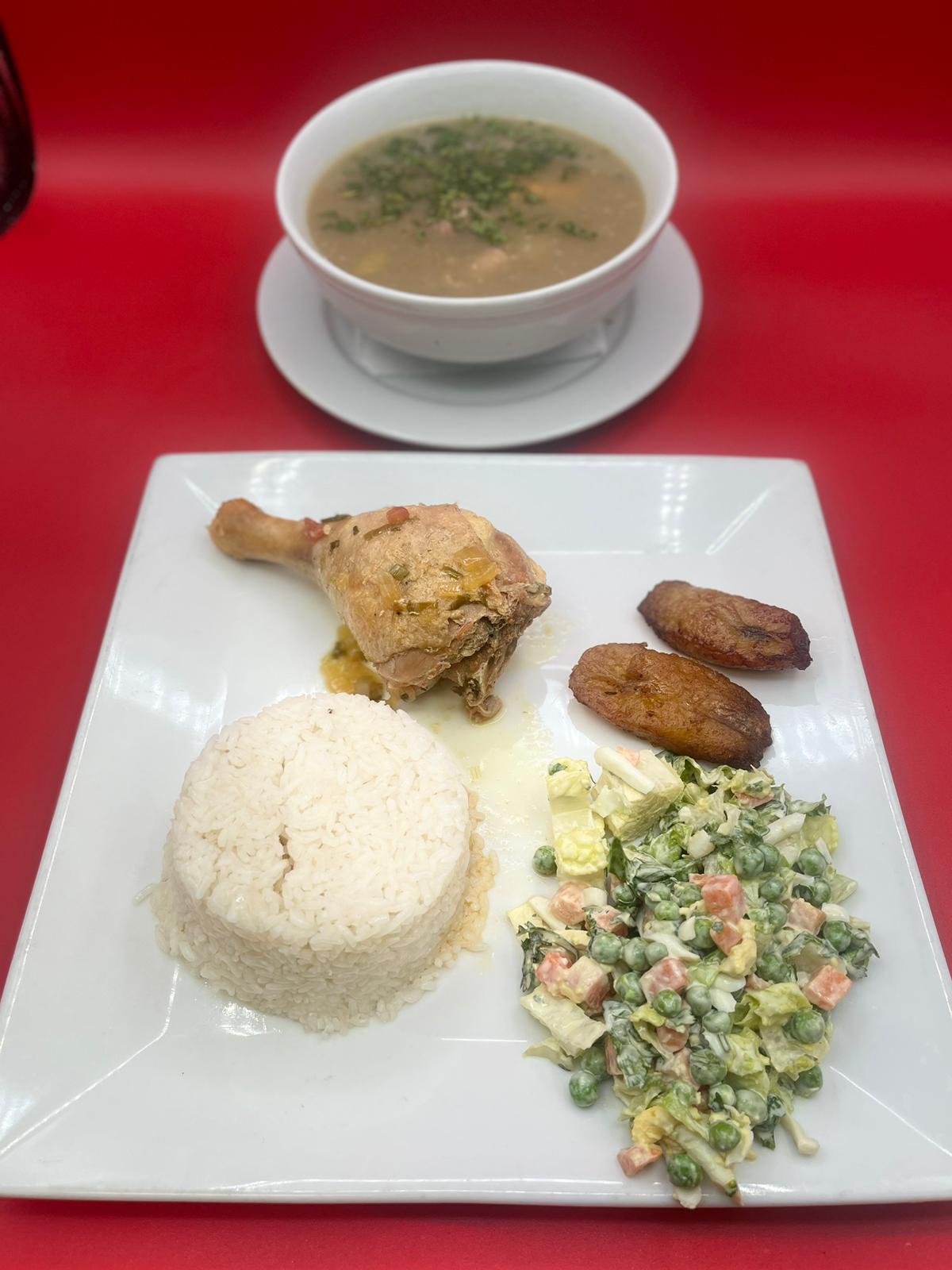 A plate of rice, chicken and soup on a red plate.