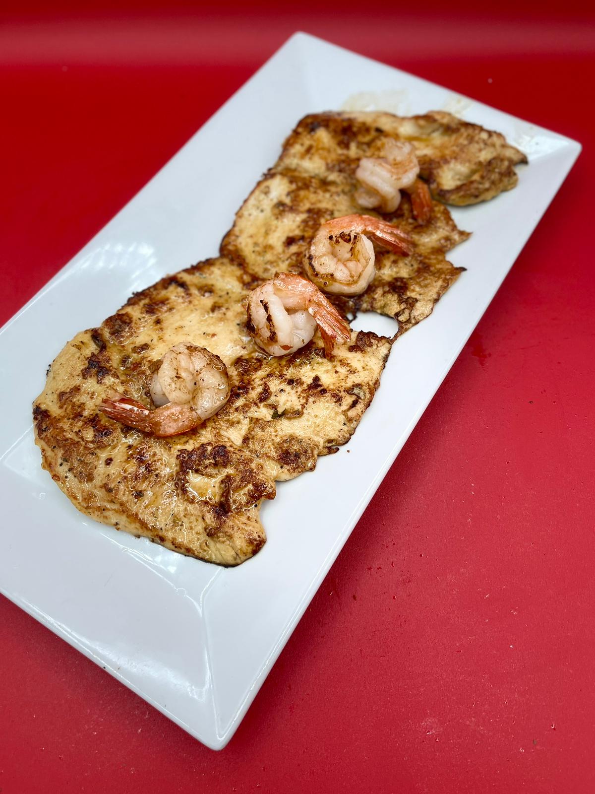 Two pancakes with shrimp on a white plate.
