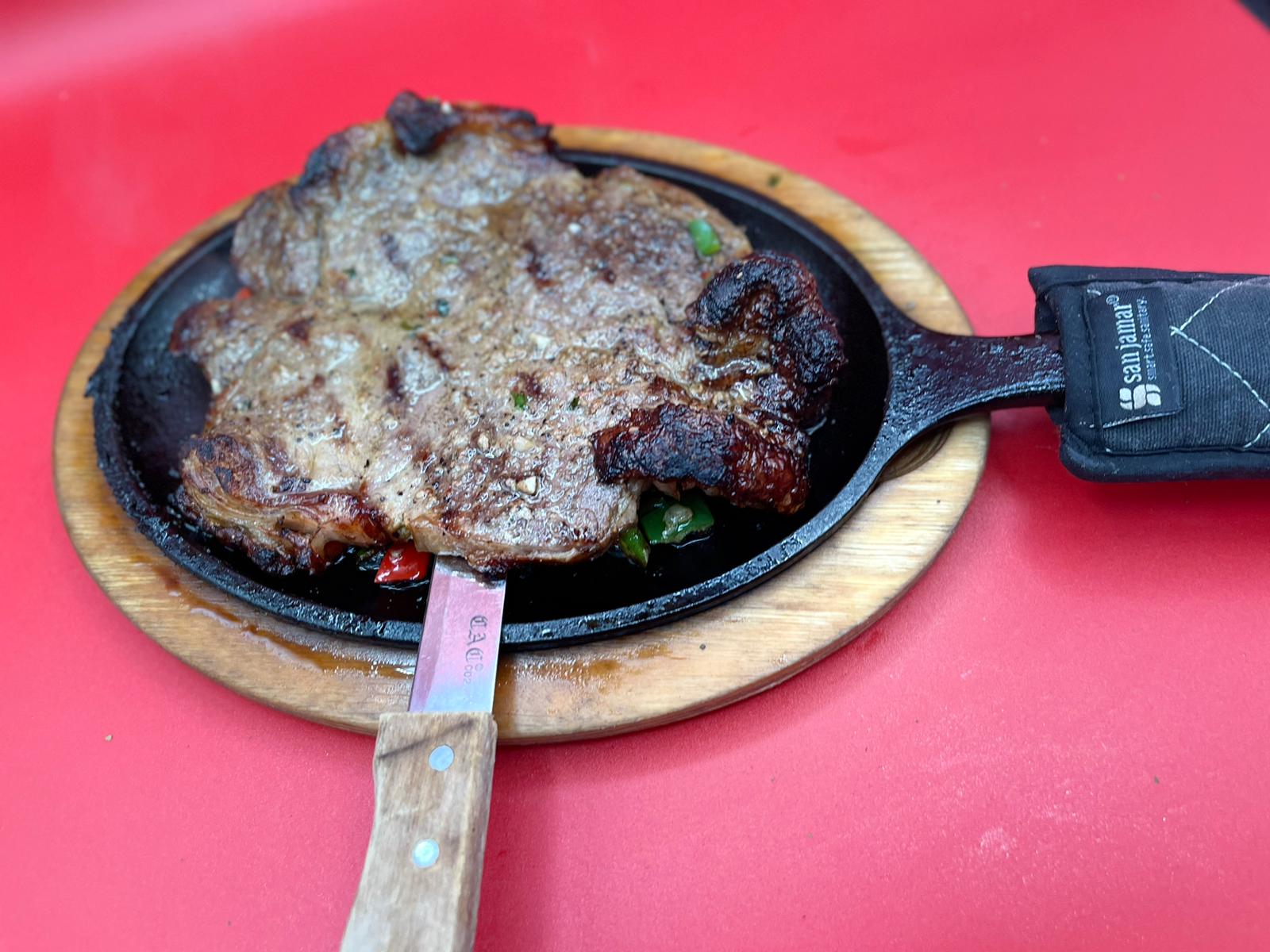 A steak in a skillet with a fork.