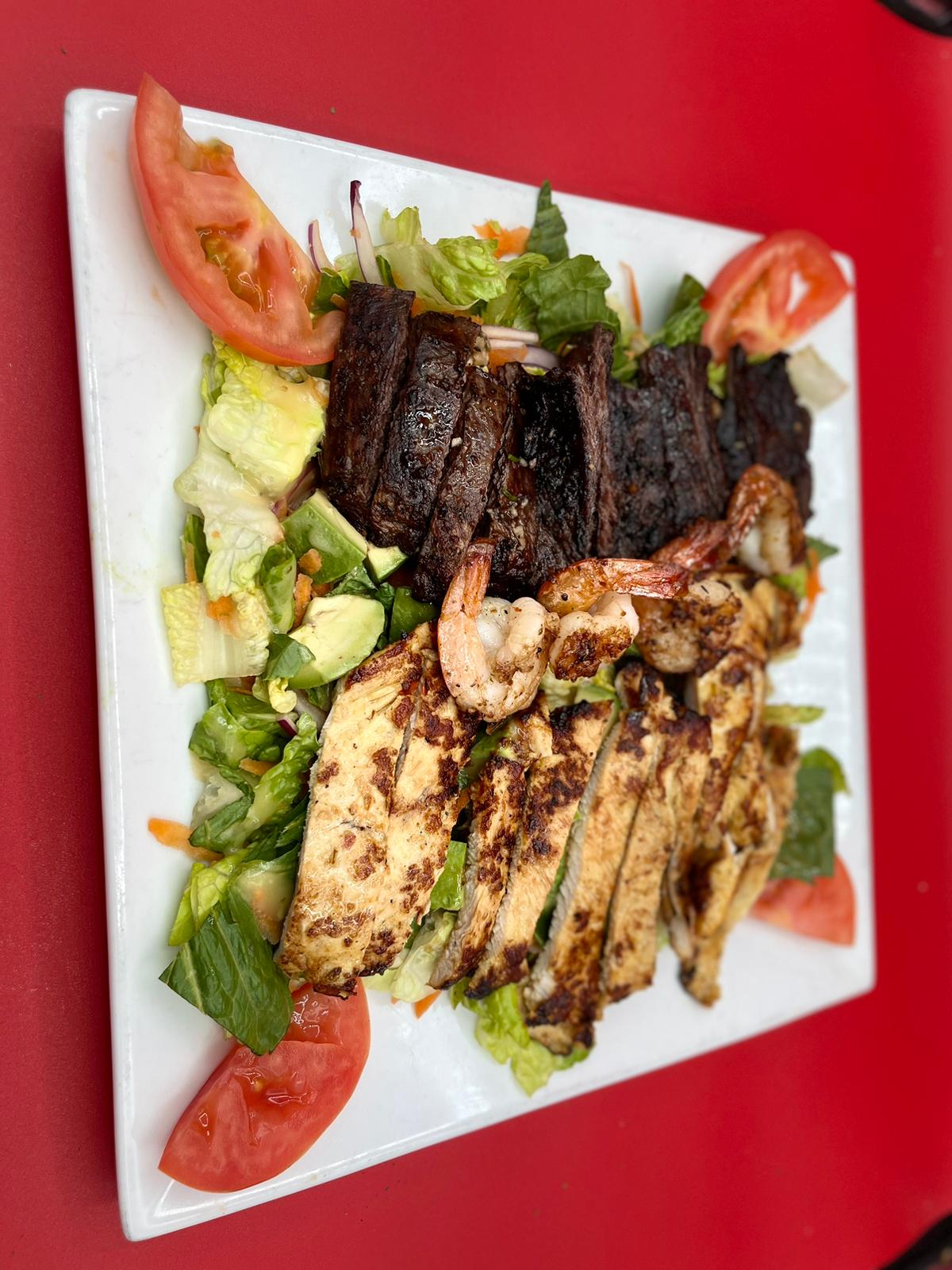 A plate of grilled meat and salad on a red plate.