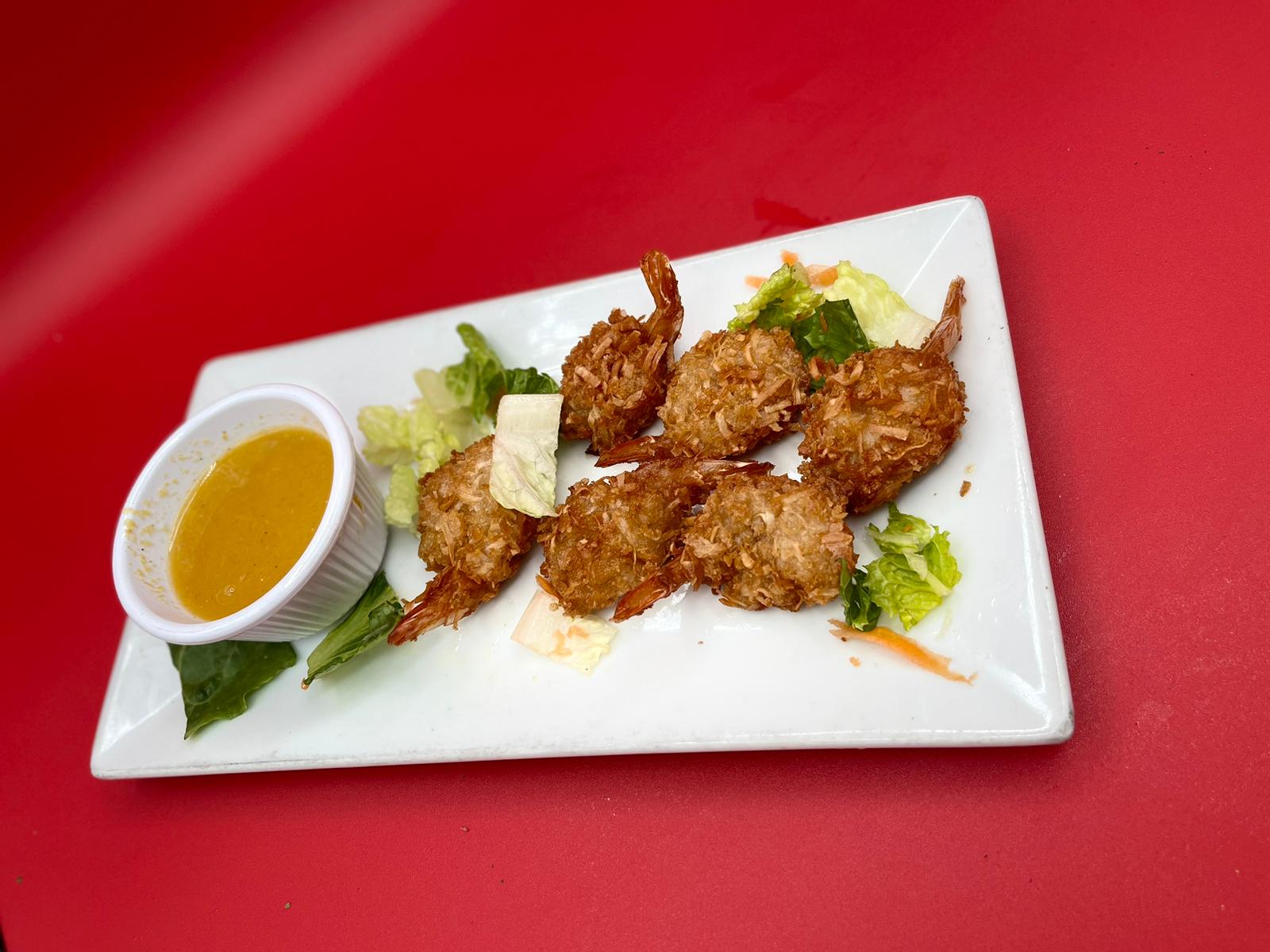 Fried shrimp with dipping sauce on a white plate.