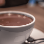 sideview of hot chocolate on a white cup on top of a table.